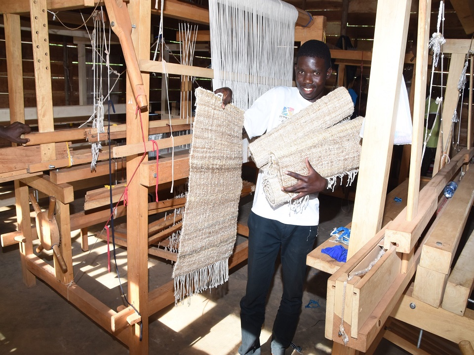A trainee cerebrates acquisition of rug weaving skills at TEXFAD